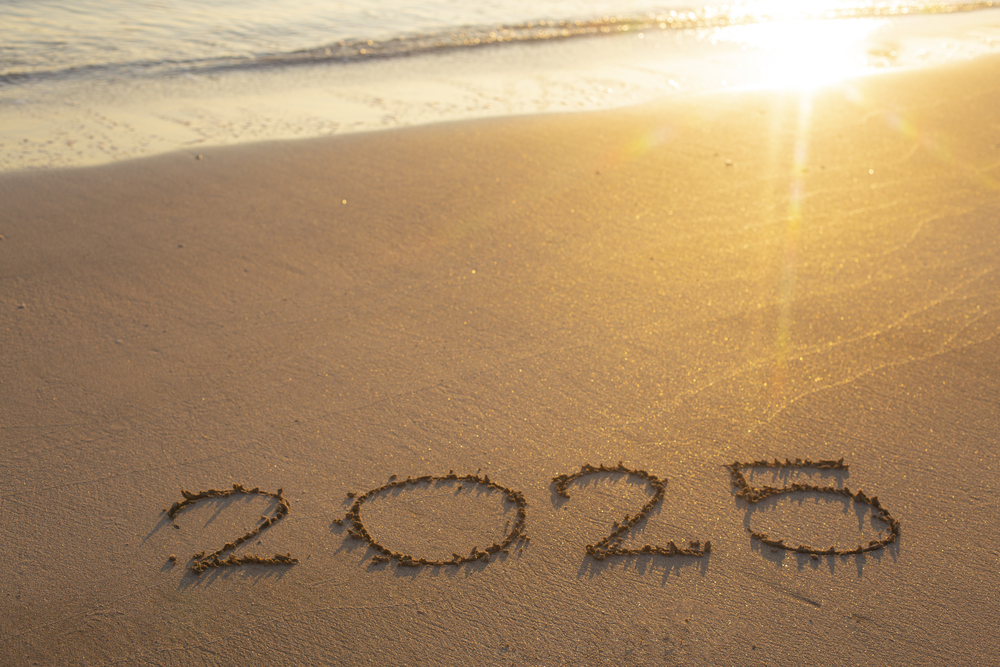 2025 written on a beach with the sun shining on it